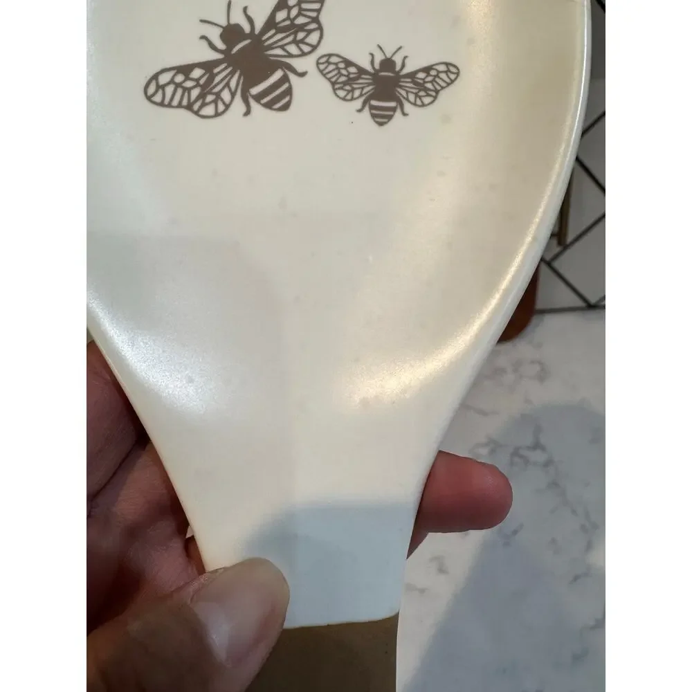 white ceramic spoon rest black bee graphic contrasting brown dipped handle